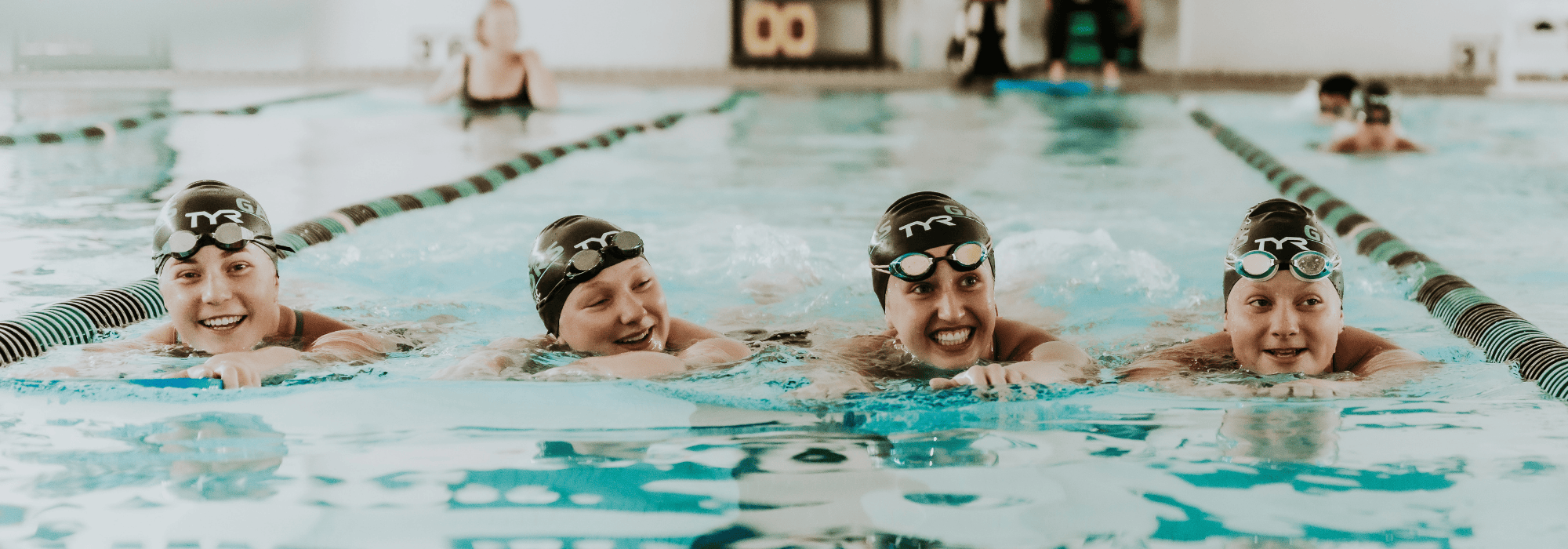 Four swimmers smiling in the pool