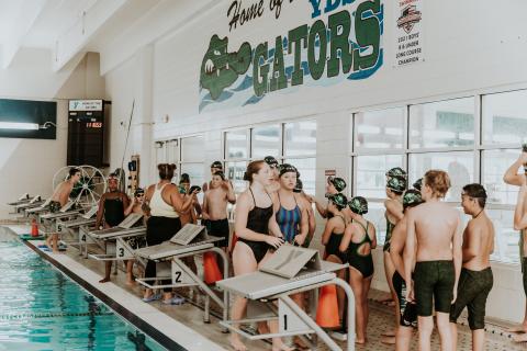Swimmers gather near the starting blocks